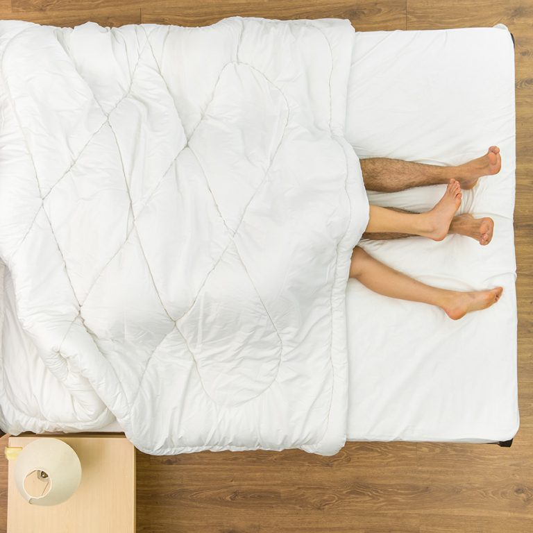 The man and woman lay under duvet. View from above